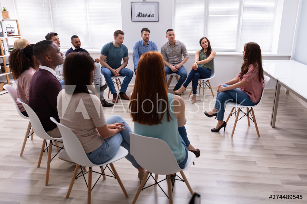 Female Therapist Speaking To Group At Therapy Section